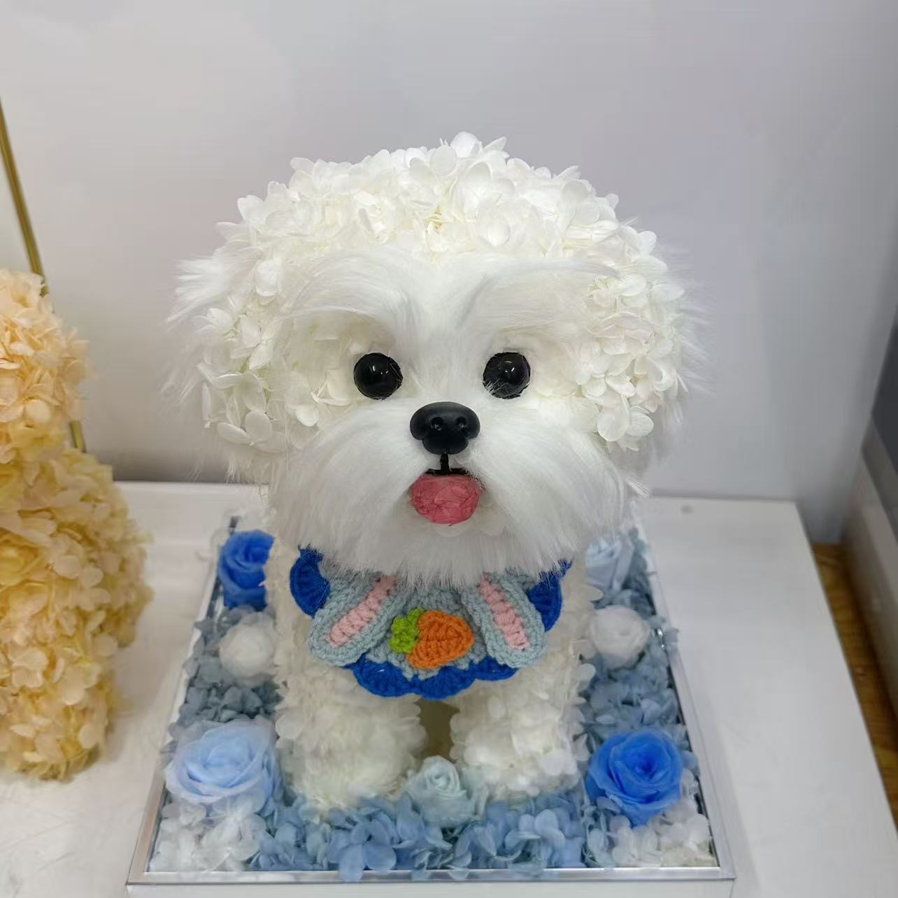 白い花びらで形づくられた犬のペットフラワーアート、青い花材を敷いたベース付き