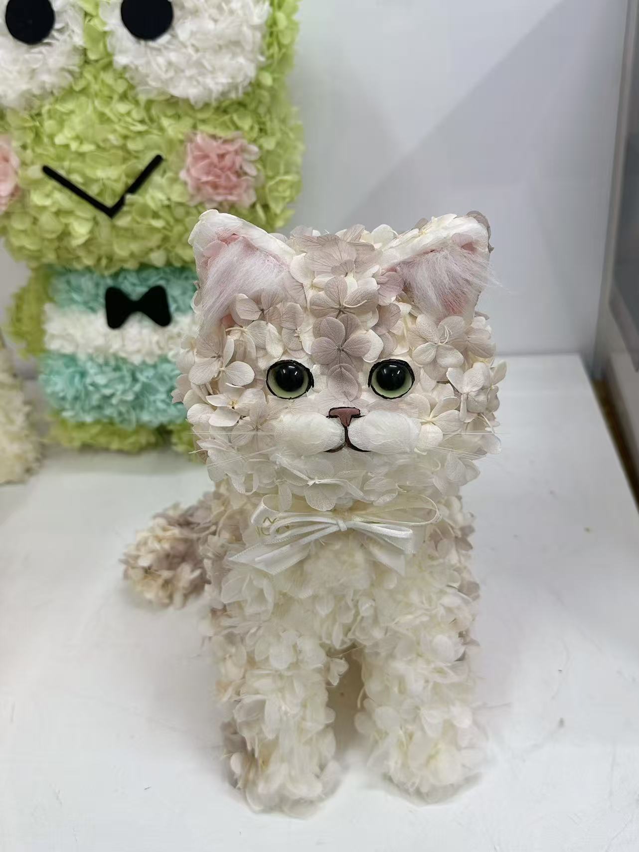 アイボリーと淡いピンクの花びらで形づくられた猫のペットフラワーアート