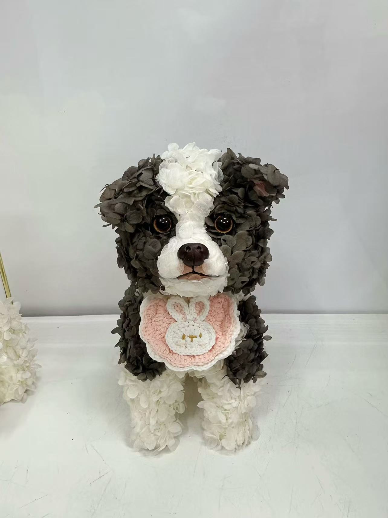 チャコールと白の花びらで形づくられた犬のペットフラワーアート